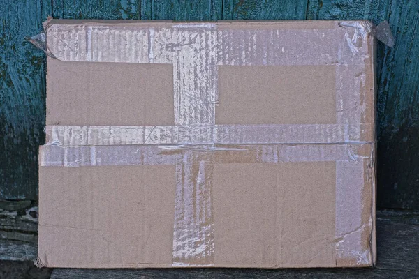 一只棕色的大纸盒靠着一面绿色的墙躺在一张灰色的桌子上 — 图库照片
