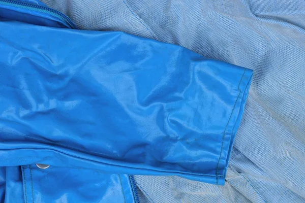 Ένα Μπλε Δερμάτινο Μανίκι Του Μπουφάν Βρίσκεται Ένα Γκρι Ύφασμα — Φωτογραφία Αρχείου