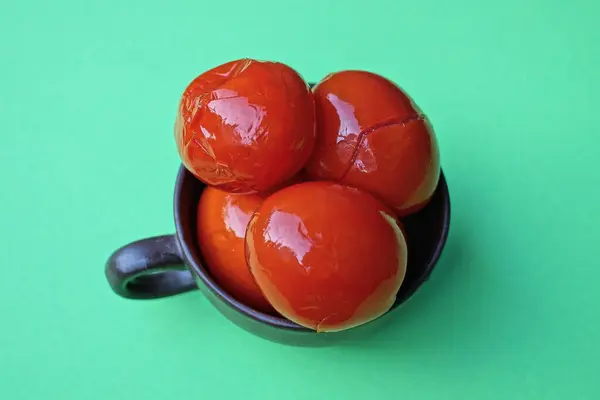 Brązowy Kubek Pełen Czerwonych Kwaśnych Pomidorów Puszce Zielonym Stole — Zdjęcie stockowe