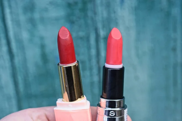 Tangan Memegang Dua Tabung Lipstik Merah Dinding Hijau — Stok Foto
