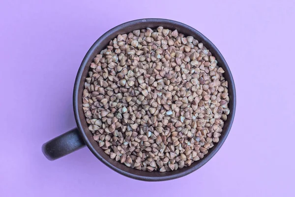 紫丁香桌上的褐色瓷杯中的干荞麦食物 — 图库照片