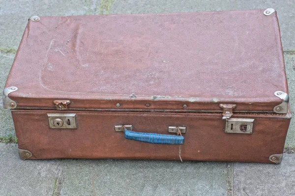 stock image one large closed brown old leather suitcase lies on gray asphalt in the street