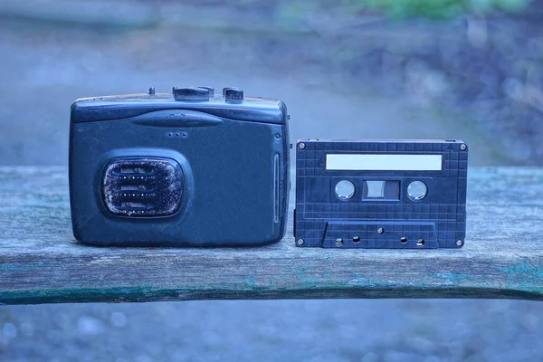 街上一张灰色的桌子上站着一个老式的黑色移动录音机和盒式磁带 — 图库照片