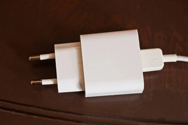 白色塑料适配器插座中带有Usb接口的电缆躺在一张褐色桌子上 — 图库照片