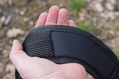 El, sırt çantasında siyah geniş bir kumaş sapı tutuyor.