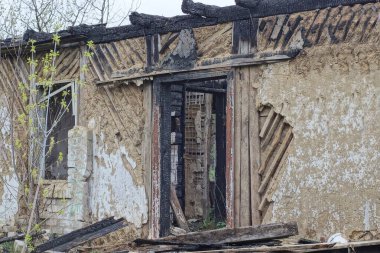 Tahta çerçeveli boş eski bir kapı yıkık dökük bir evin kahverengi bir duvarında, sokakta çıkan yangından sonra yanmış.
