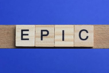 Ahşap gri harflerden yapılmış destansı kelime mavi bir arka planda yatıyor.