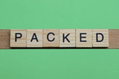 Sözcük, yeşil kağıt arka planda küçük, gri ahşap harflerden oluşuyor.