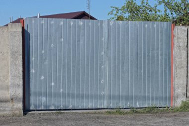 Sokağın beton duvarında kapalı gri metal bir kapı var.