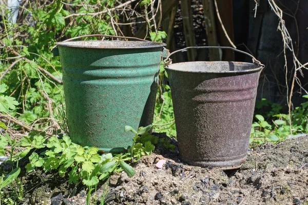 在街上的绿色草丛中 灰色的土地上矗立着两个旧的 肮脏的金属搪瓷桶 — 图库照片