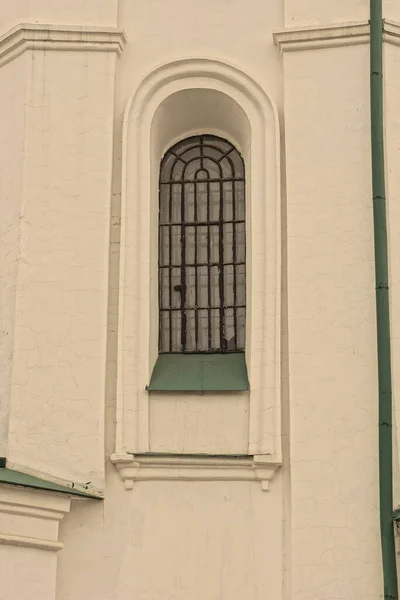 街上一座建筑物的白色石墙上的一个黑色铁栅栏后面的一个旧窗户 — 图库照片
