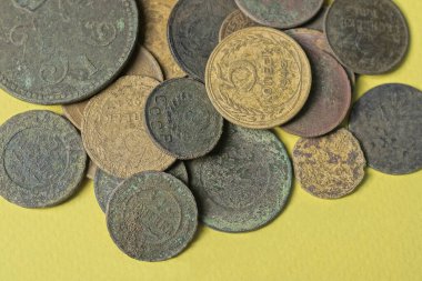 Sarı bir masanın üzerinde eski bir para yığını var.