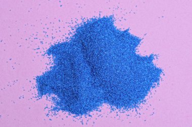 sarı bir masanın üzerinde küçük bir dekoru mavi kum yığını.