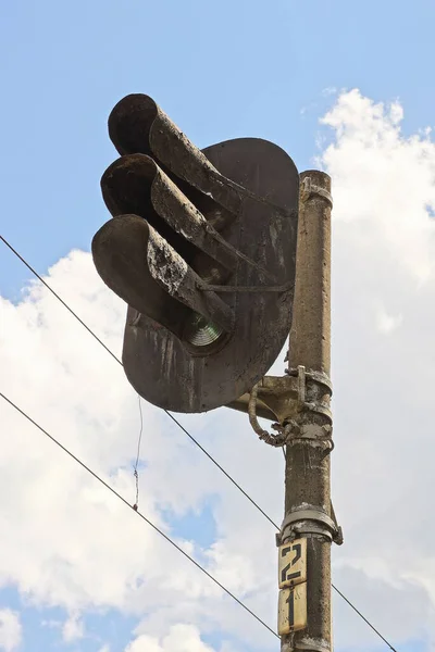 在蓝色的天空和云彩映衬下灰色混凝土柱子上的一条黑色铁路线的红绿灯 — 图库照片