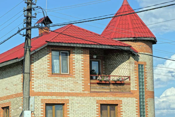 青い空に向かって通りの赤い瓦屋根の下に窓とオープンバルコニーのある民家の茶色い屋根裏部屋 — ストック写真