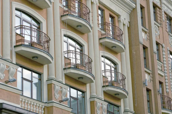 街の通りにガラス窓やドアがある大きな家の石壁に開いた茶色の鉄のバルコニーの列 — ストック写真