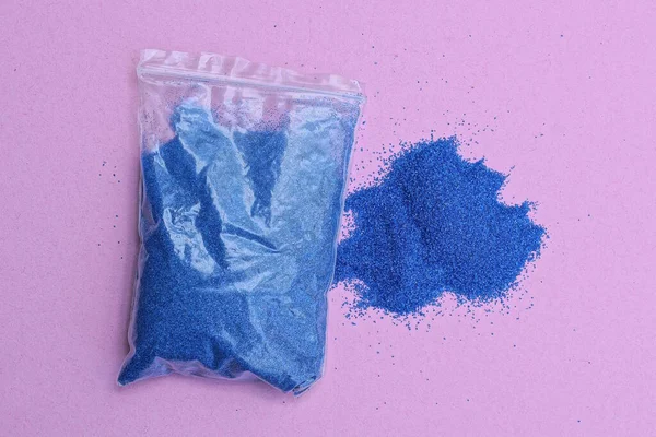 Одна Маленька Відкрита Пластикова Сумка Синім Піском Рожевому Столі — стокове фото