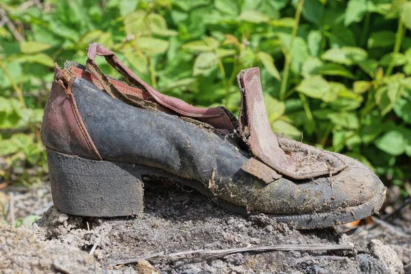 Один Старый Порванный Коричневый Черный Грязный Ботинок Стоит Серой Земле — стоковое фото