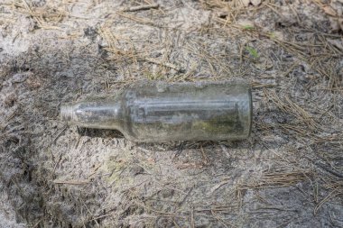 Kirli, eski bir cam şişeden çıkan çöpler sokaktaki gri zeminde yatıyor.