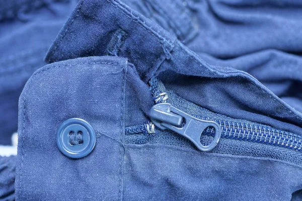 閉じたジップと青い布の上の1つのプラスチックボタン服 — ストック写真