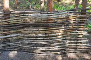 Sokaktaki gri dallardan yapılmış dekoratif bir hasır çitin parçası.