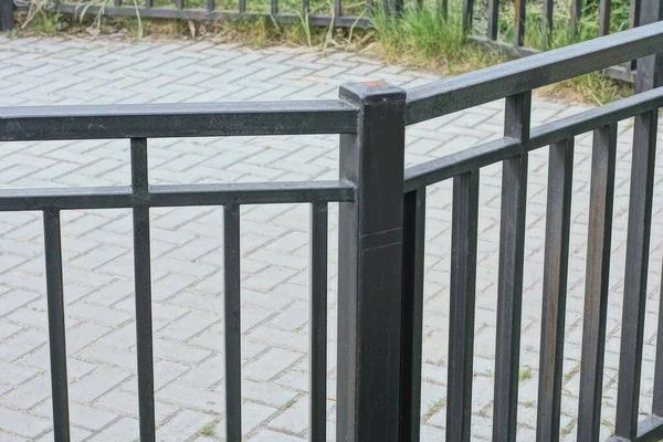 灰色の歩道を背景に通りに黒い鉄の棒で作られた黒い金属製の装飾フェンスの一部 — ストック写真