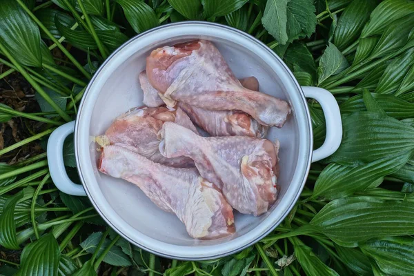 Їжа Купи Сирих Курячих Ніжок Білій Сковороді Стоїть Зеленому Листі — стокове фото