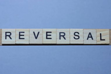 Gri bir masada siyah yazı tipi olan kahverengi ahşap harflerin tersini yaz.