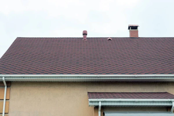 灰色の空に面した民家の茶色のタイル張りの屋根の上にレンガの煙突が一つ — ストック写真