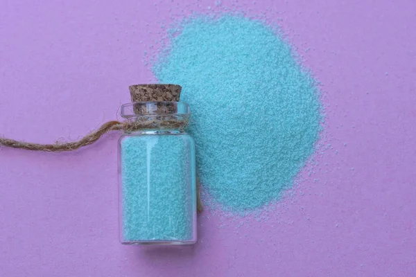 Одна Маленька Декоративна Скляна Пляшка Синім Піском Лежить Купі Фіолетовому — стокове фото