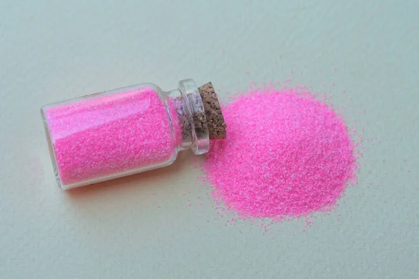 一个装有粉色沙子的装饰玻璃瓶堆在一张灰色桌子上 — 图库照片