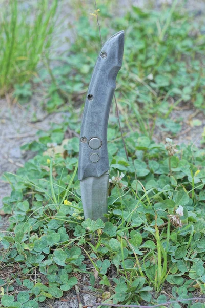 一条古老的灰色金属折叠刀在街上的绿色草丛中伸出地面 — 图库照片