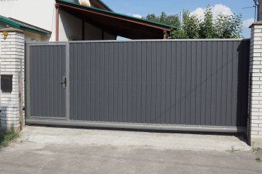 Siyah demir kapı ve kapalı metal kapı kırsal bir sokakta beyaz tuğlalı bir duvarda.