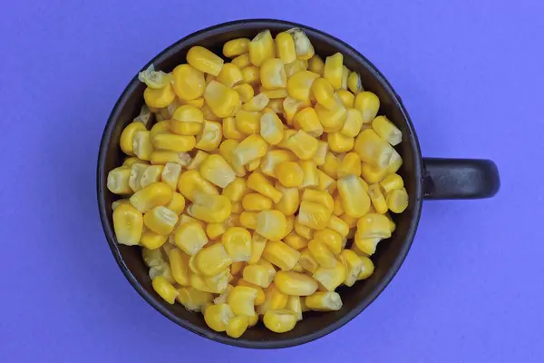 褐色瓷杯中的黄色玉米食品倒立在丁香桌上 — 图库照片