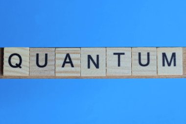 Kelime kuantum ahşap gri harflerden yapılır mavi bir arka planda yatar