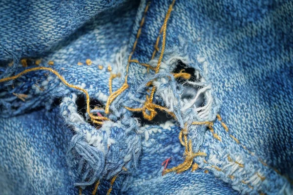 古い服の縫い目に穴と黄色の糸で裂かれた青い白い綿の生地の一部からのテクスチャ — ストック写真