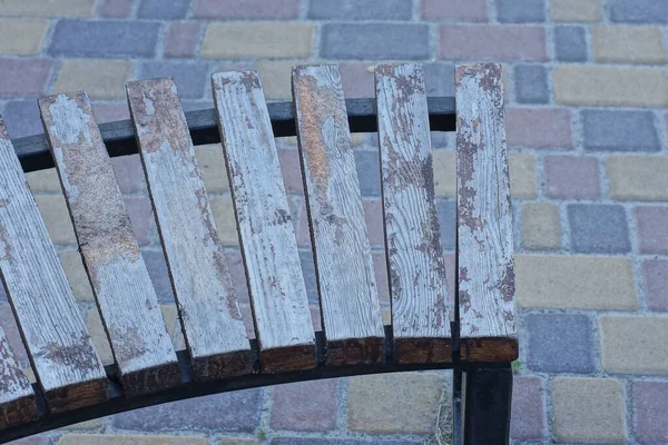 木製の板で作られた灰色のベンチの一部が通りの茶色の歩道に立っています — ストック写真