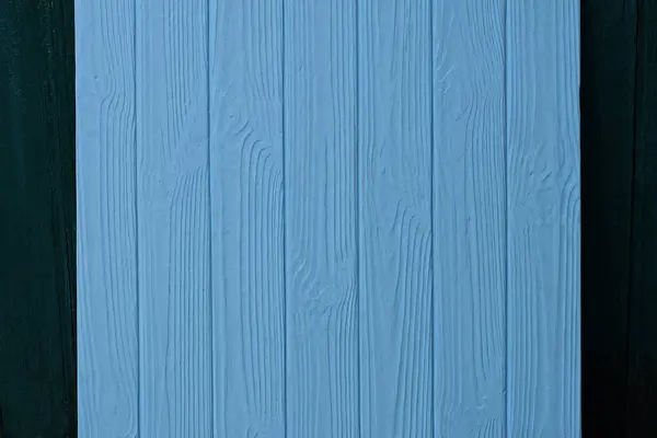 木製の板で構成された青い四角形の電話パネルが緑の壁に向かって立っています — ストック写真