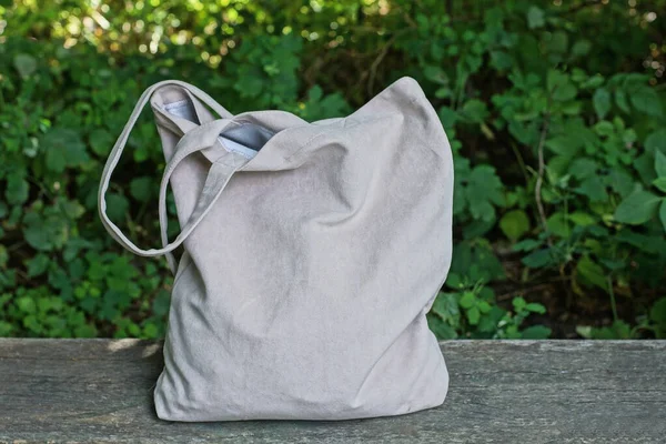 stock image one large full gray bag stands on a wooden table on the street against the backdrop of green vegetation