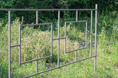 Sokaktaki yeşil çimlerde demir parmaklıklardan yapılmış gri metal bir çitin parçası.