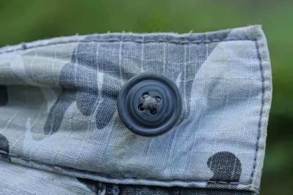 绿色背景衣服上灰色面料上的一个大的黑色塑料钮扣 — 图库照片