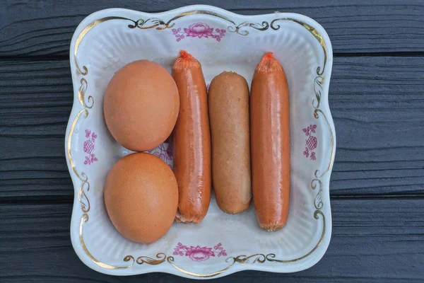 Comida Três Linguiças Fervidas Dois Ovos Frango Marrons Uma Chapa — Fotografia de Stock