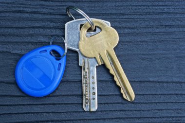 Metal bir yüzükteki üç kapı anahtarı siyah bir ahşap masada yatıyor.