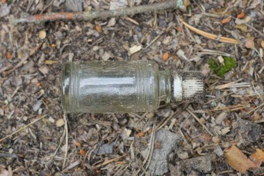 Kirli beyaz kapaklı küçük bir şişe şişe şişe sokakta gri zeminde yatıyor.