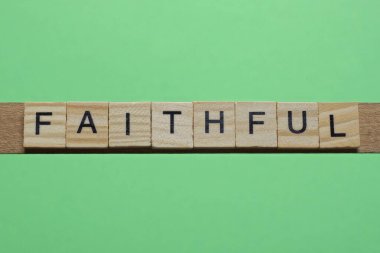 Sadık kelimesi yeşil kağıtta küçük tahta harflerden oluşur.