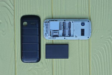 Ayrıntılı eski bir parçalanmış telefon sarı ahşap bir masada yatıyor.
