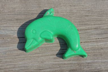 Plastik yeşil, küçük, kirli bir yunus sokakta, tahta bir masanın üzerinde yatıyor.