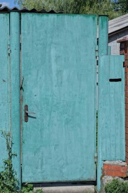 Bir demir kapı ve kırsal bir sokakta yeşil metal çit.