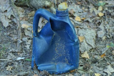 Bir yaz caddesinde gri zeminde mavi, eski, kırık bir plastik kutu duruyor.