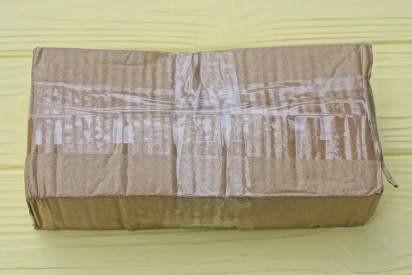 Ein Brauner Papiergeschlossener Rechteckiger Paketkarton Liegt Auf Einem Gelben Holztisch — Stockfoto
